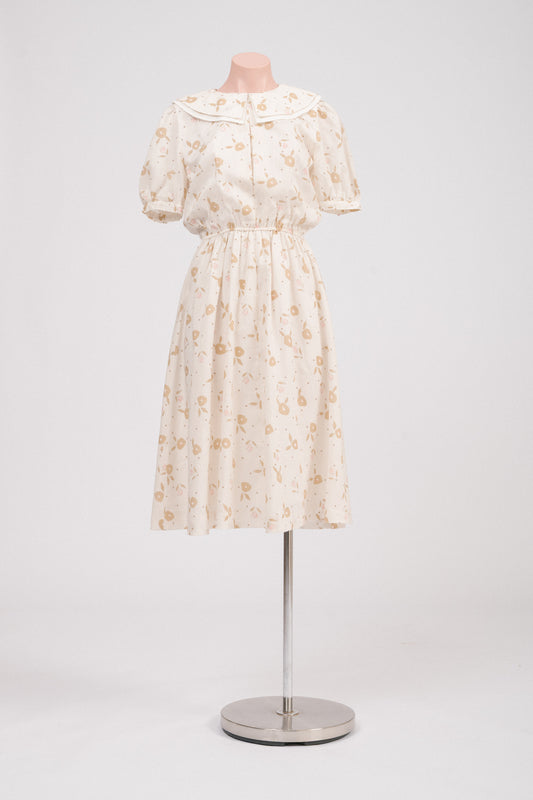 Front view of vintage floral midi dress with Peter Pan collar in cream, pink, and golden tones.
