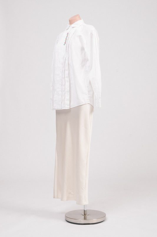 Side angle of vintage white floral embroidered blouse highlighting structured cotton fabric and high neckline.