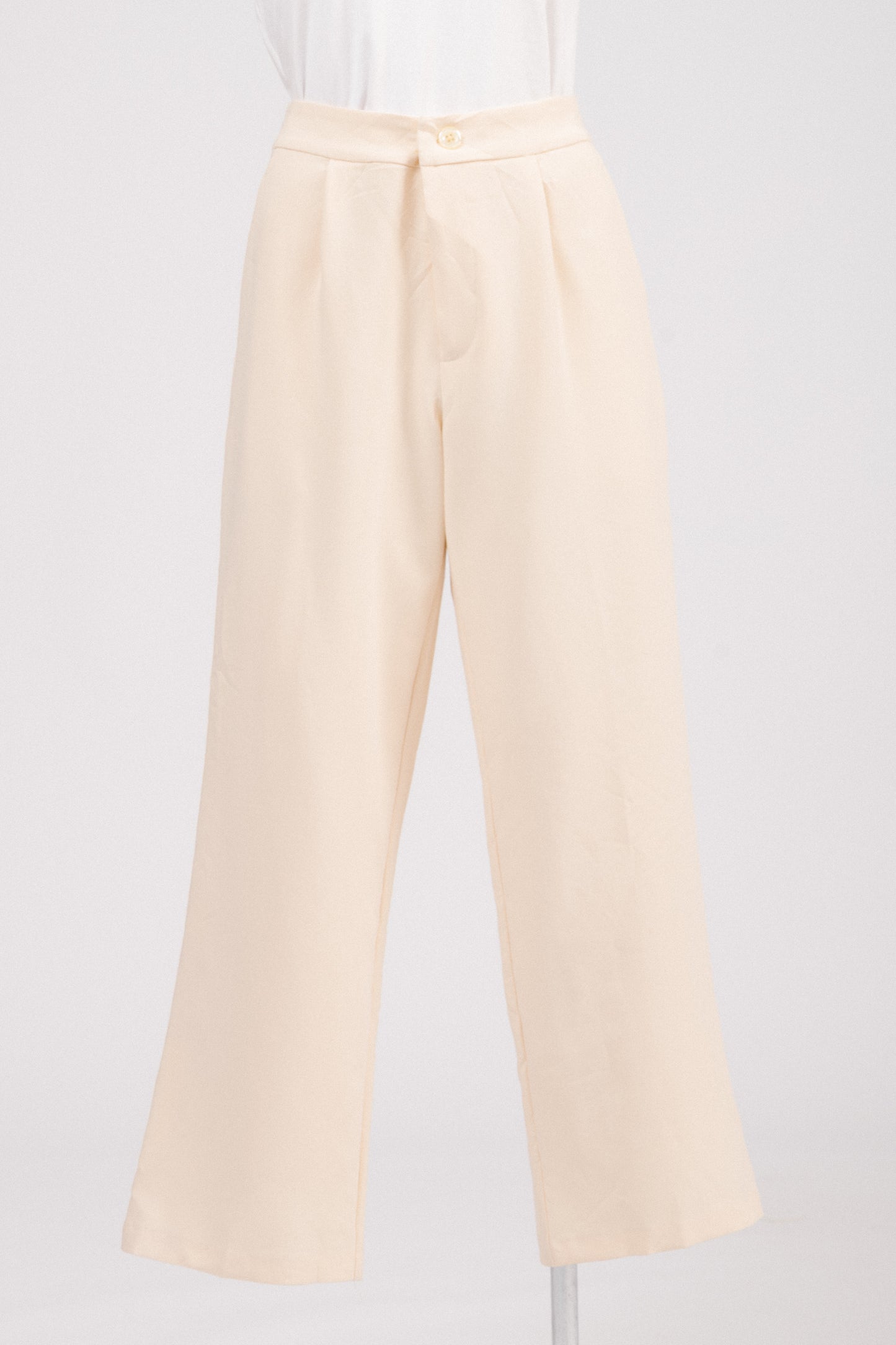 Close-up of textured fabric and pearl-style button on tailored pants.