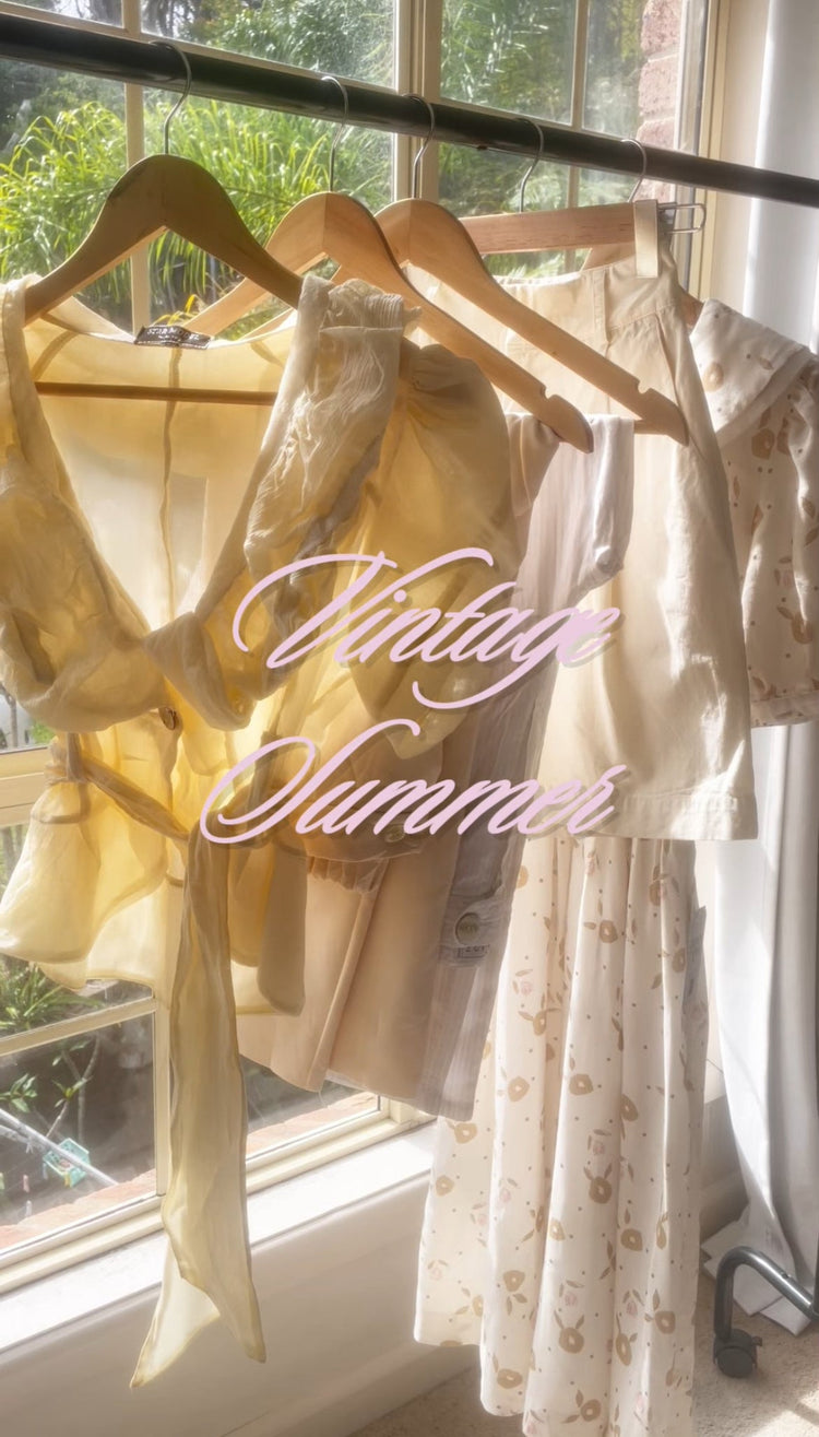 Women’s vintage clothing Australia. Vintage Summer Collection 2025 by Lemon Lane Vintage. Sunlit display of feminine preloved clothing including Butter Yellow Ruffle Blouse, Buttercream Shorts, Cotton-Linen Pants, and Cottagecore Babydoll Dress.