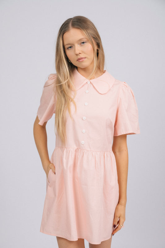 Vintage cottage core baby pink babydoll mini dress with peter pan collar, midi-length sleeves, front white buttons, and pockets front view - Lemon Lane Vintage
