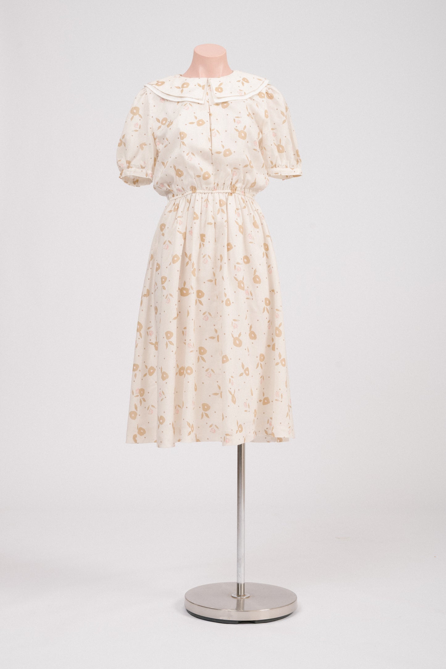 Front view of vintage floral midi dress with Peter Pan collar in cream, pink, and golden tones.