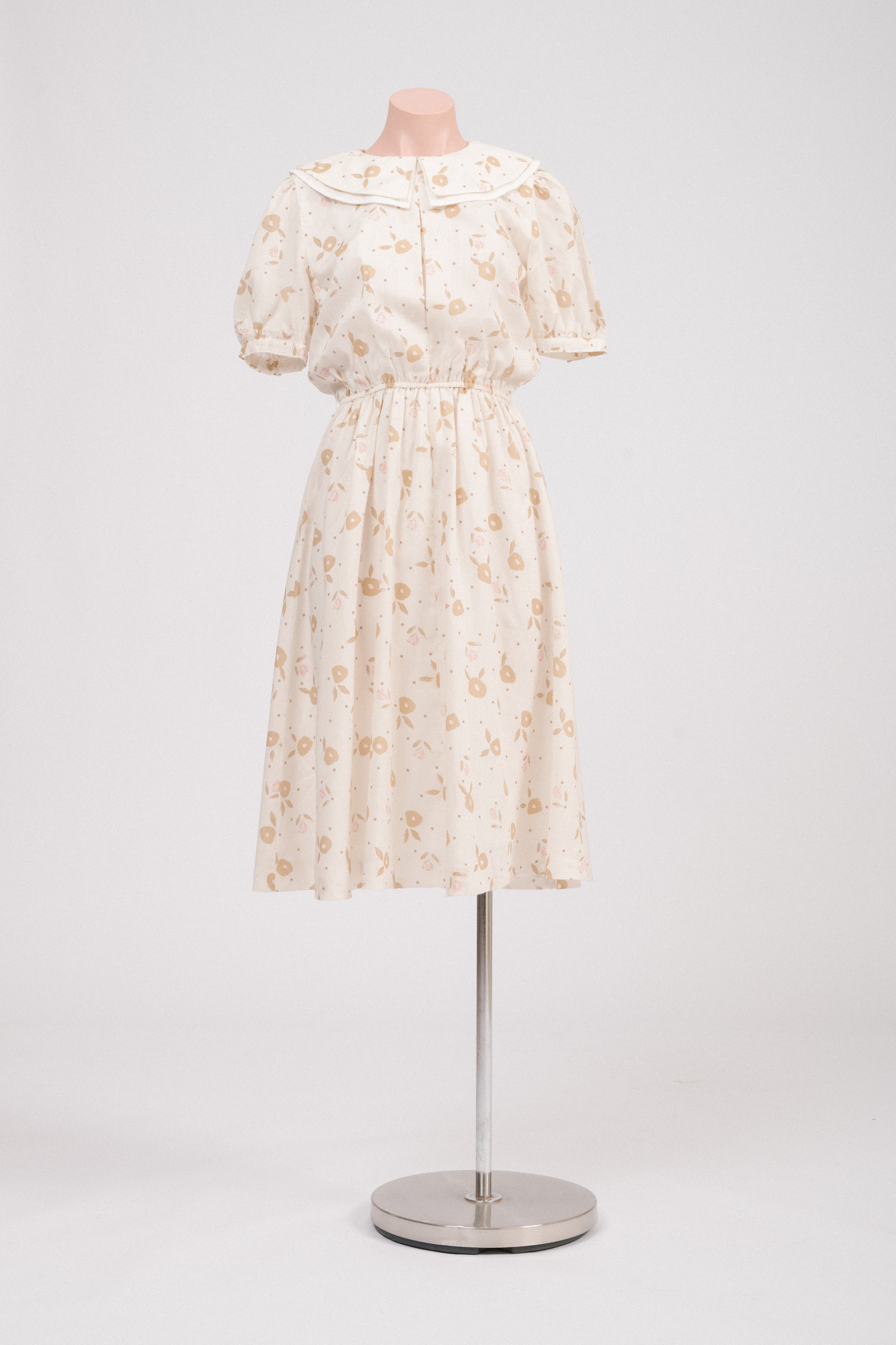 Front view of vintage floral midi dress with Peter Pan collar in cream, pink, and golden tones.