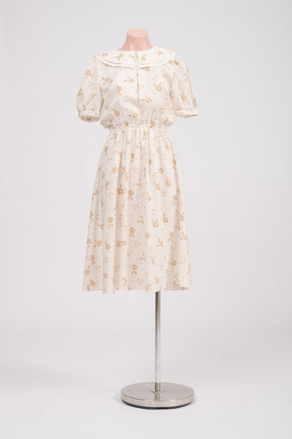 Front view of vintage floral midi dress with Peter Pan collar in cream, pink, and golden tones.