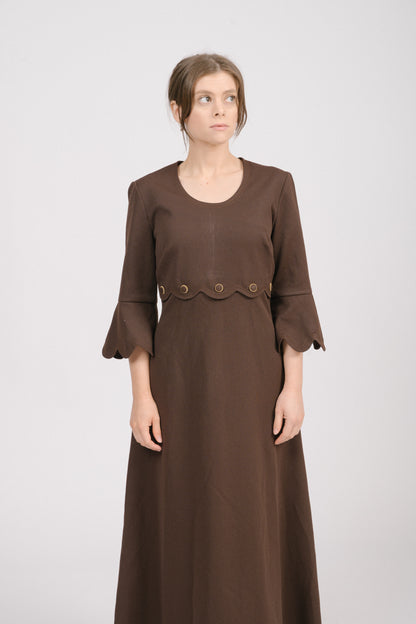 Close-up of scalloped neckline trim and gold-trim decorative buttons on vintage brown dress.