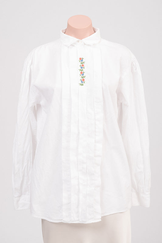 Vintage white cotton blouse with floral embroidery and concealed button placket photographed front-on against a neutral background.