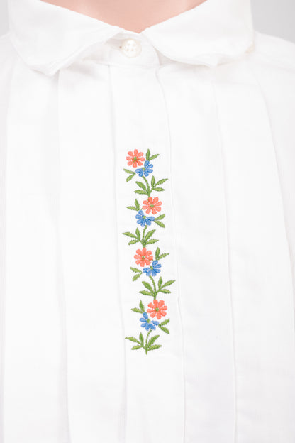 Close-up of floral embroidery and concealed button placket on vintage white cotton blouse showing ribbed fabric texture and heirloom detailing.