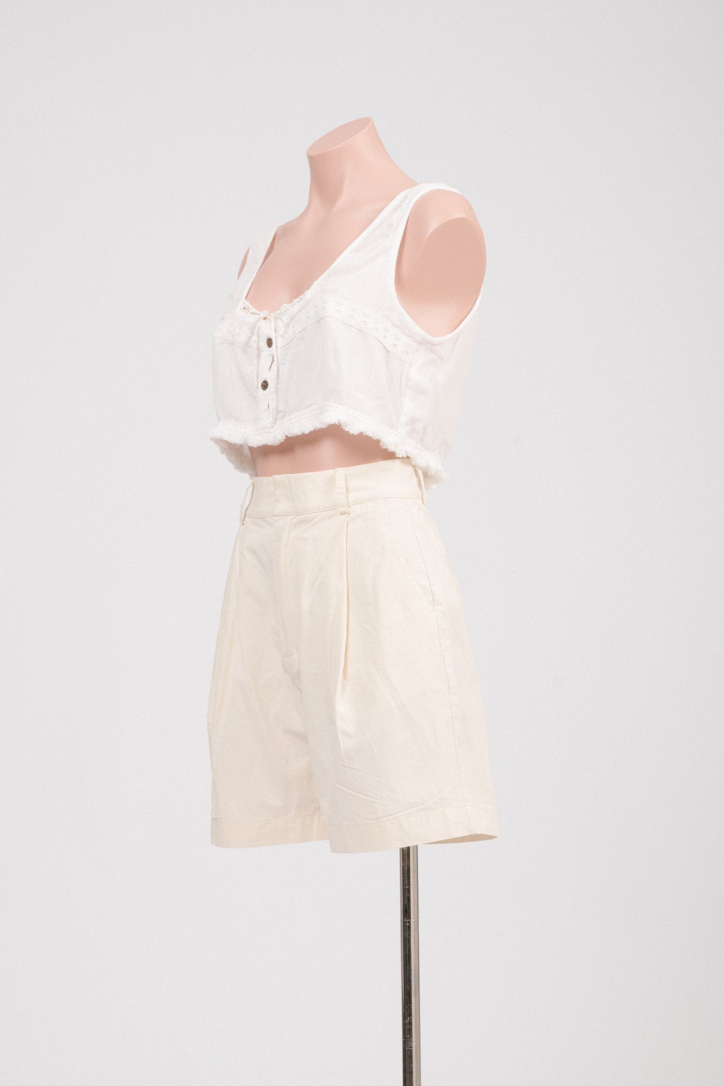 Detail of waistband, pockets, and cotton fabric texture on preloved buttercream shorts.