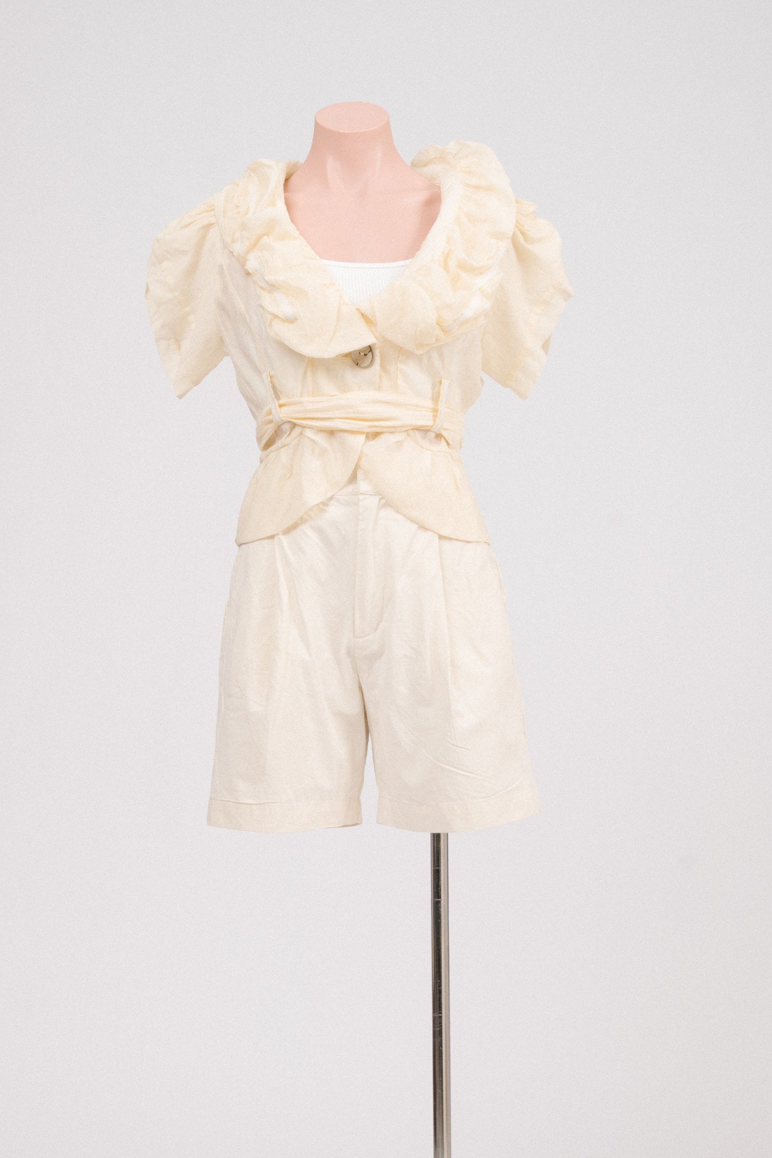 Vintage butter yellow ruffle blouse with waist tie displayed front-on.