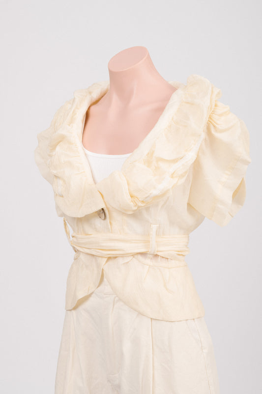 Close-up of ruffled collar and wooden button detail on vintage yellow blouse. Detail of tulip cap sleeve with gathered seam and soft puff shoulder.