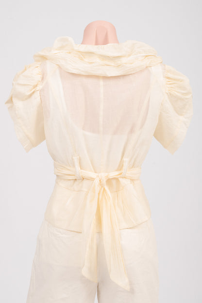 Back view of vintage butter yellow blouse showing curved high-low hem and ruffle panel.
