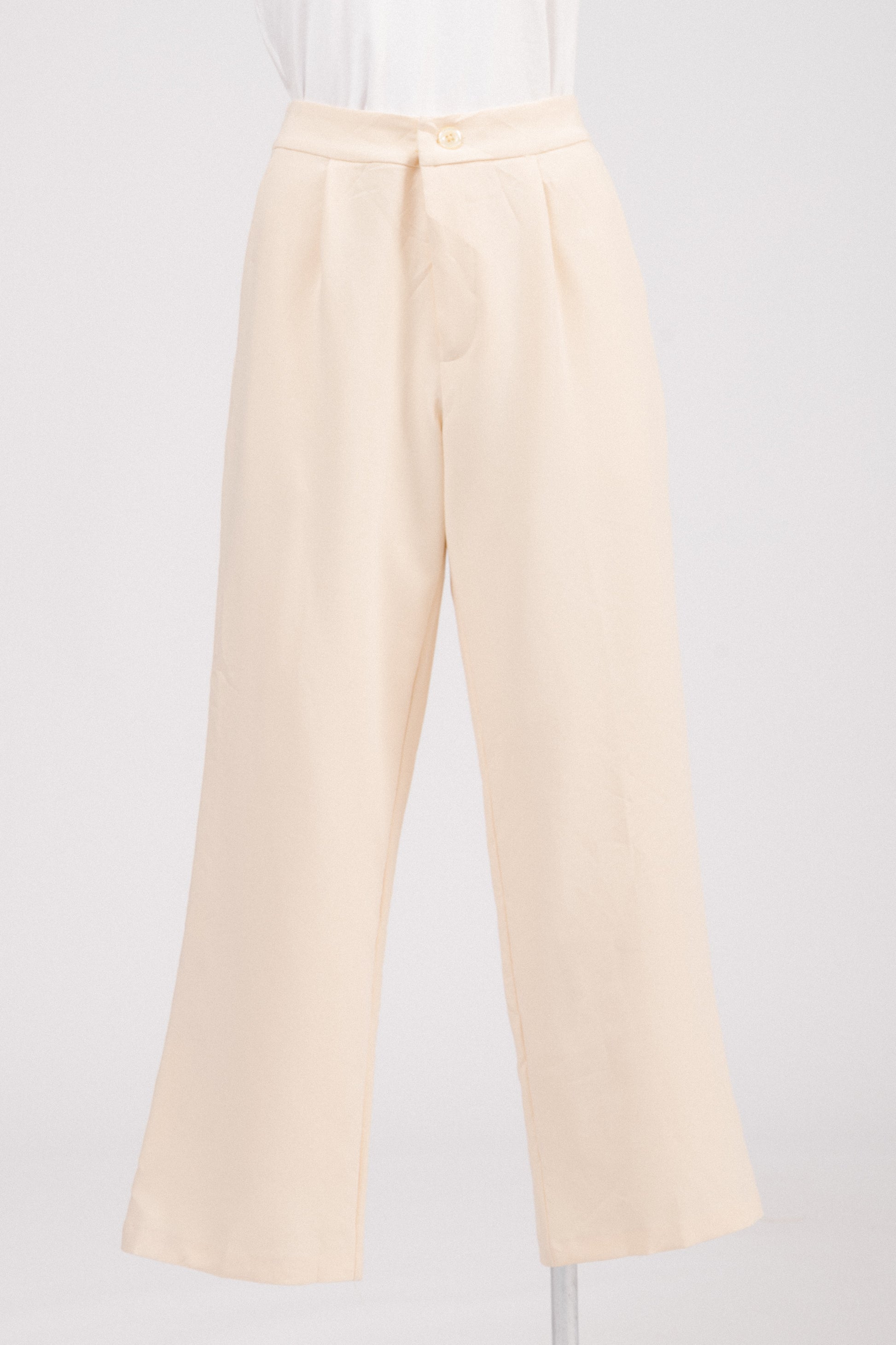 Close-up of textured fabric and pearl-style button on tailored pants.