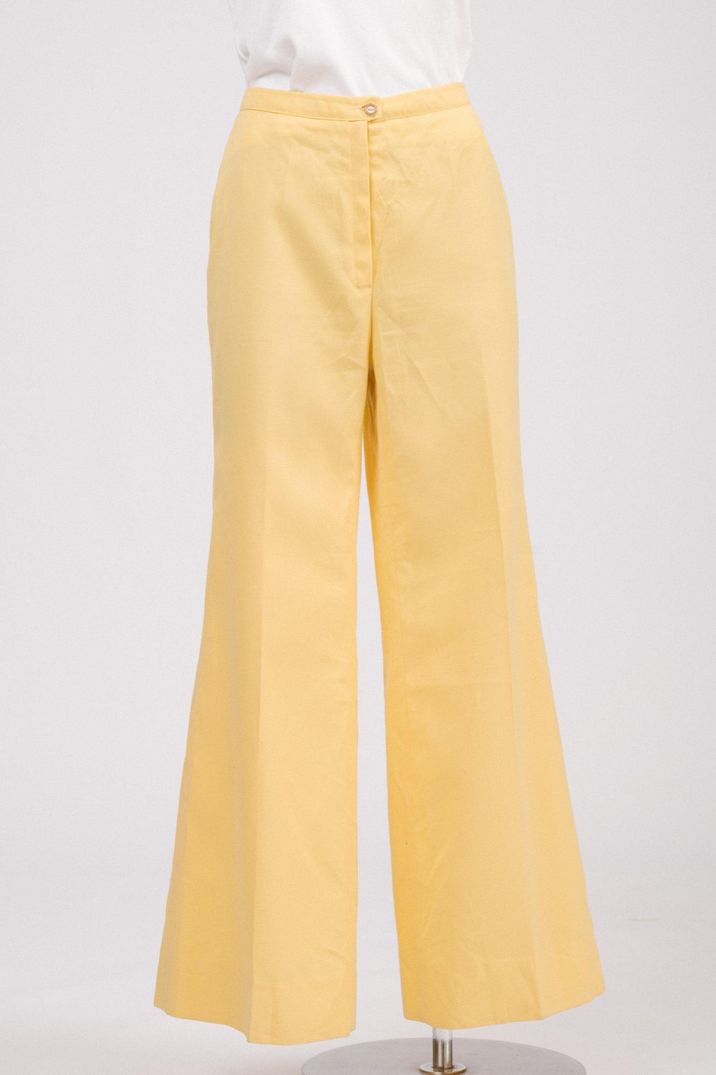 Close-up of vintage 70s yellow flare pants fabric and centre front lapped zipper with coordinating button, showcasing quality polyester mélange and retro tailored finish.