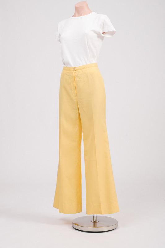 Side profile of vintage 70s yellow flare pants, highlighting structured fit and flared leg silhouette, perfect retro tailored trousers for feminine wardrobe.