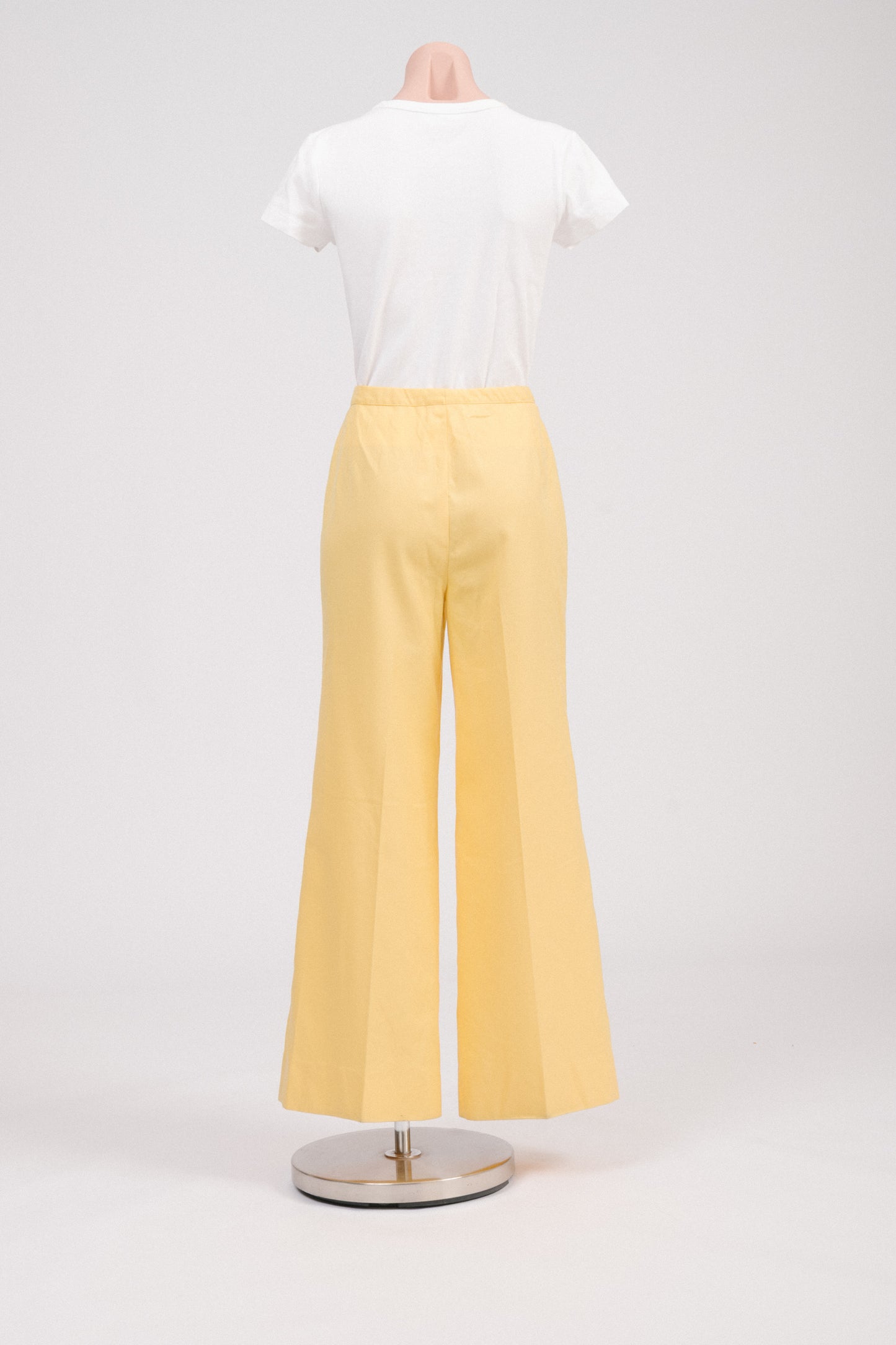 Back view of vintage 70s sunshine yellow flare pants, showing clean tailored back, flared hem, and classic retro polyester fabric for summer or work outfits.