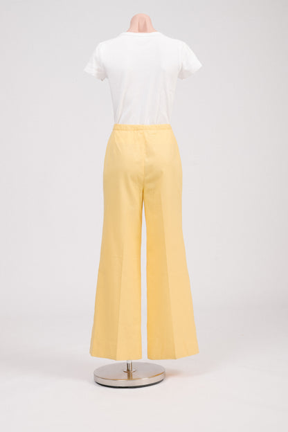 Back view of vintage 70s sunshine yellow flare pants, showing clean tailored back, flared hem, and classic retro polyester fabric for summer or work outfits.